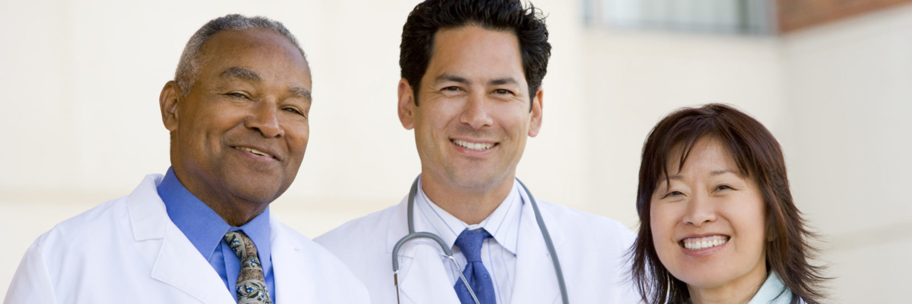 three doctors standing outside a hospital